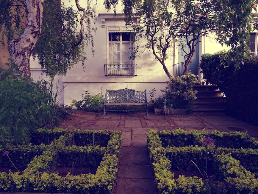 A wooden garden door painted in a natural wood tone is set within a dense wall of green ivy and climbing plants. The ivy features small, dark green, glossy leaves that create a thick curtain over the